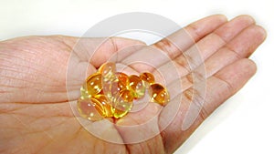 Hand holding Cod liver oil or fish oil gel capsules on white  background.