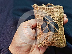 A hand holding a coffee car perfume filled with coffee beans, packaged in an aesthetically pleasing rough burlap material photo