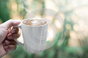 Hand holding coffee cup on bokeh nature background