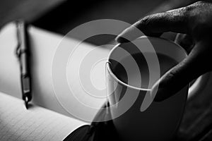 Hand holding a coffee mug with a journal