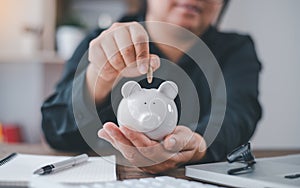 Hand holding coin with pig piggy bank. Saving and financial accounts concept