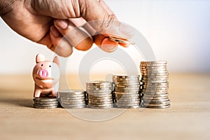 A hand holding coin to saving money for future with piggy bank on stack money,Success of life in future