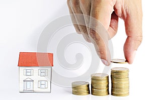 Hand holding coins put on coins stack and house paper on white backgrounds for mortgage loan concept