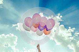 Hand holding colorful balloons on blue sky background