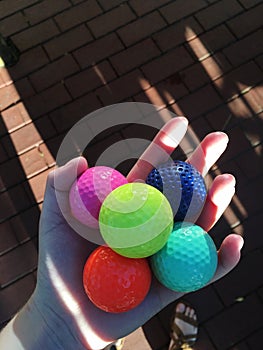 Hand holding colorful golfballs