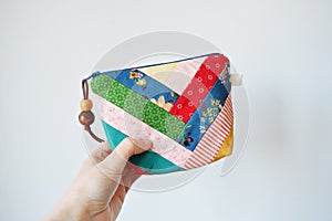 Hand holding colorful patchwork notions bag with zipper and wooden beads