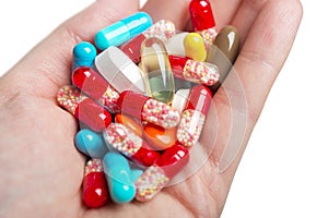 A hand holding coloured pills and capsules.