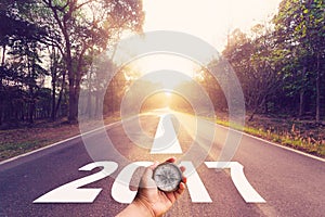 Hand holding compass on Empty asphalt road and New year 2017 concept