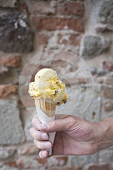 Hand holding cone with yellow ice cream. Banana chocolate