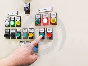 Hand holding the control panel of the industrial plant and pushing or turning the button in electrical selector switch,button