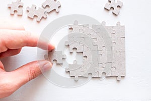 Hand holding the correct part of the puzzle on a white background