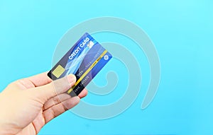 Hand holding credit card on blue background - payment online shopping paying with credit card technology e wallet concept