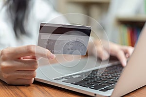 Hand holding credit card and using computer online for shopping or paying bills