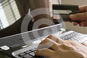 Hand holding a credit card and using laptop