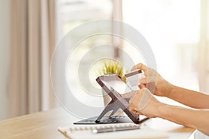 Hand holding a credit card and using tablet pc