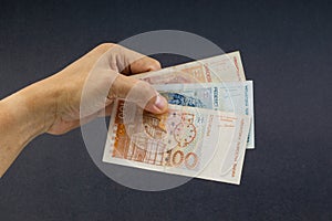Hand holding Croatian KUNA or STO KUNA bank notes on black background.