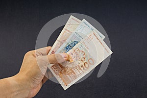 Hand holding Croatian KUNA or STO KUNA bank notes on black background.