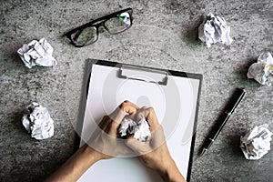 Hand holding crumpled paper balls with eye glasses and file folder on desk office