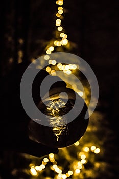 Hand holding a crystal ball with the reflection of a shiny Christmas tree