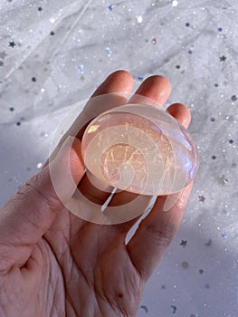 Hand holding crystal pink quartz aura.