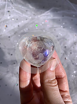 Hand holding crystal quartz aura.