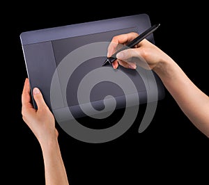 Hand holding digital graphic pen and drawing graphic tablet isolated on black