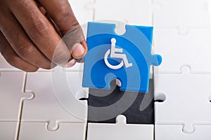 Hand Holding Disabled Wheelchair Icon On Jigsaw Puzzle