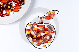 Hand holding drawing apple with colorful capsules and pills on white background. Health care vitamins or synthetic food concept.