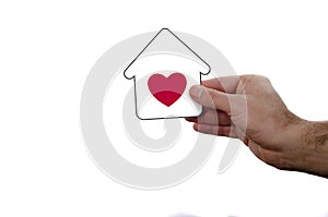 hand holding dream house icon with red heart over a whi