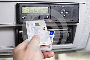 Hand holding a driver digital card and Europian driving licence infront of a digital tachograph. No personal data photo