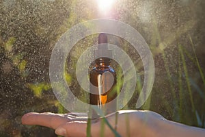 Hand holding a dropper bottle with oil herbal remedy inside. Blurred background creates a calming effect