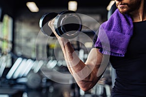 Hand holding dumbbell.Close up.Muscular arm in the gym.