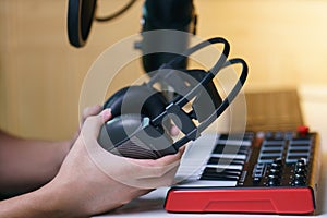 Hand holding earphone near sound mixing console board. Equipment for the music studio