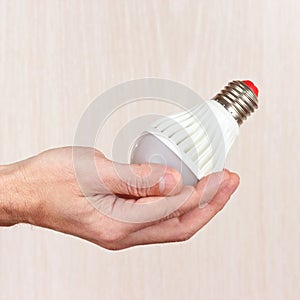 Hand holding ecofriendly led lightbulb on light wood background