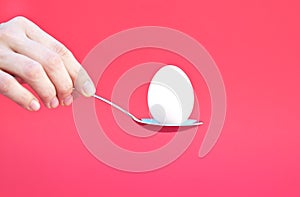 Hand holding an Egg with a Spoon