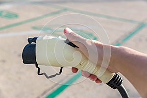 Hand holding Electric car charger. Electric Vehicle EV Charging station & Charger. Human hand is holding Electric Car Charging con