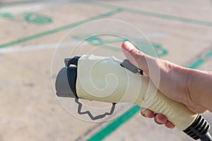 Hand holding Electric car charger. Electric Vehicle EV Charging station & Charger. Human hand is holding Electric Car Charging con