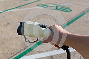 Hand holding Electric car charger. Electric Vehicle EV Charging station & Charger. Human hand is holding Electric Car Charging con