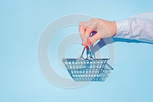 hand holding empty metal shopping basket.