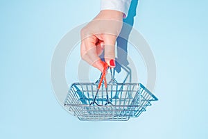 hand holding empty metal shopping basket.