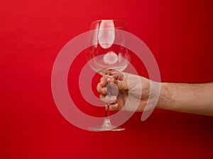 Hand holding an empty wine glass on background. Side view with space for copying. Concept of holiday backgrounds