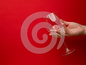 Hand holding an empty wine glass on background. Side view with space for copying. Concept of holiday backgrounds