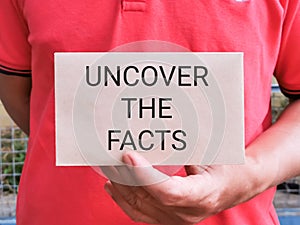 Hand holding envelope with text UNCOVER THE FACTS