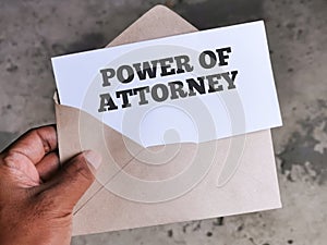 Hand holding envelope with white card written text POWER OF ATTORNEY.