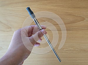 Hand holding an Environmentally friendly medium sized stainless steel metal reusable straw