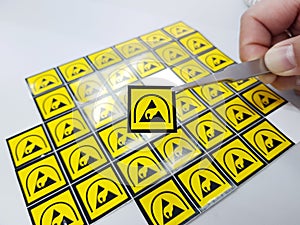 Hand holding ESD symbol label with tweezers,Electrostatic Sensitive Devices (ESD) in electronic industrial.
