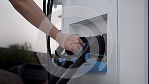 Hand holding EV charging plug in front of camera with blurred background