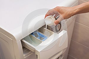 Hand holding fabric softener in washing machine