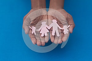 Hand holding family figure cutout top view. World health day Protection against domestic violence, healthcare and medical