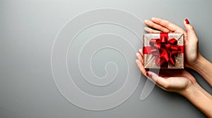 Hand holding a festive holiday gift against a solid silver background